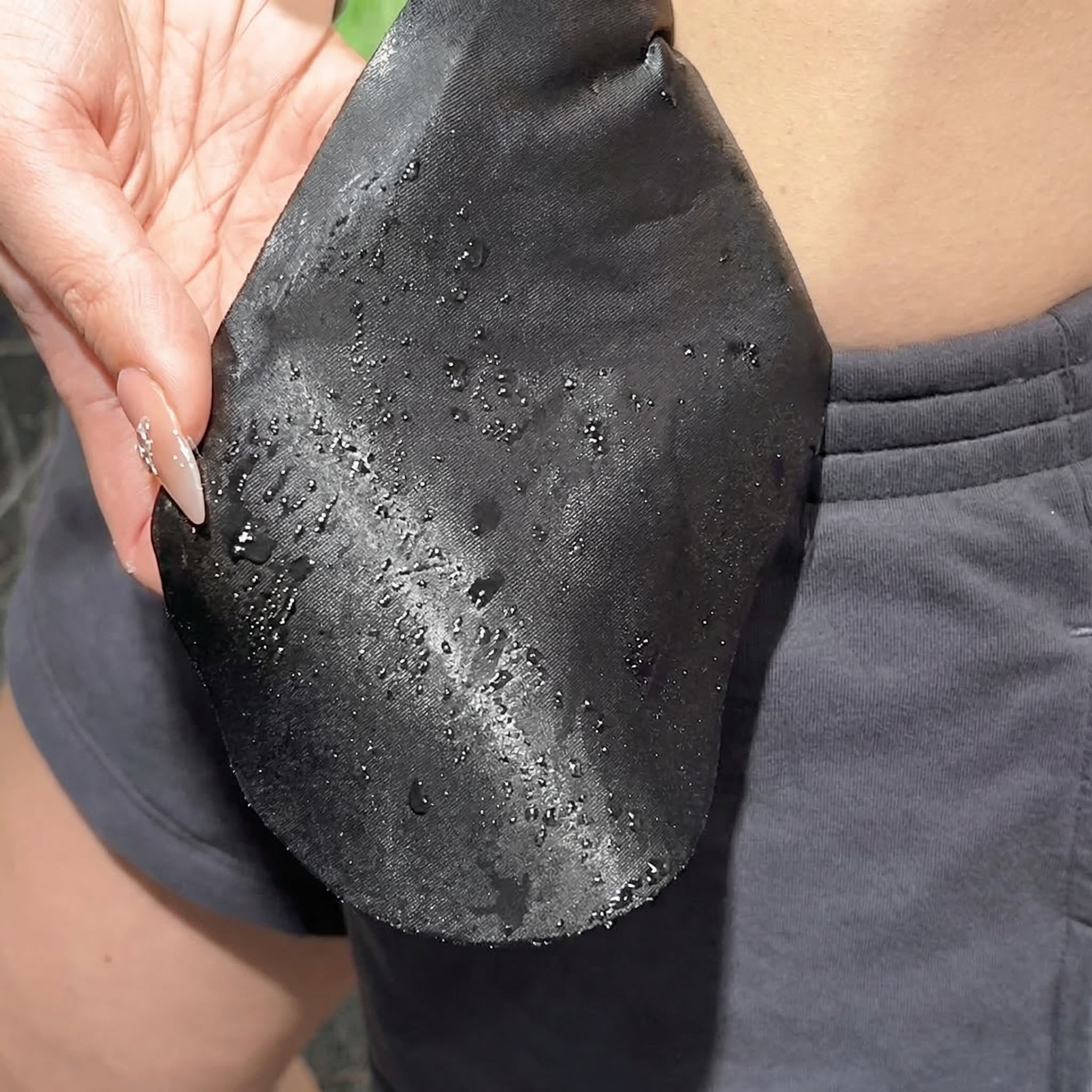 Person holding a black, textured object with water droplets on it.
