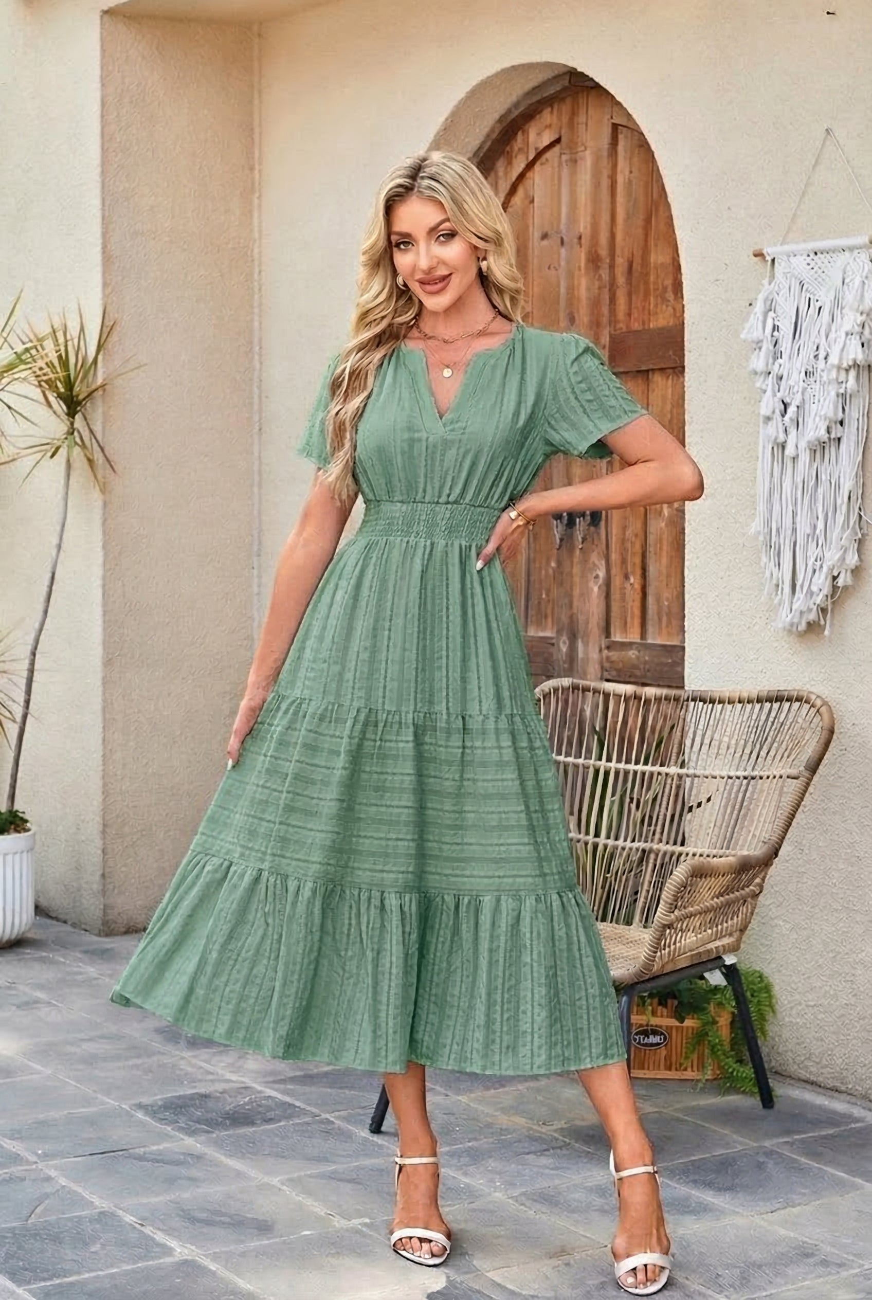 Woman wearing a green dress standing in front of a wooden door.